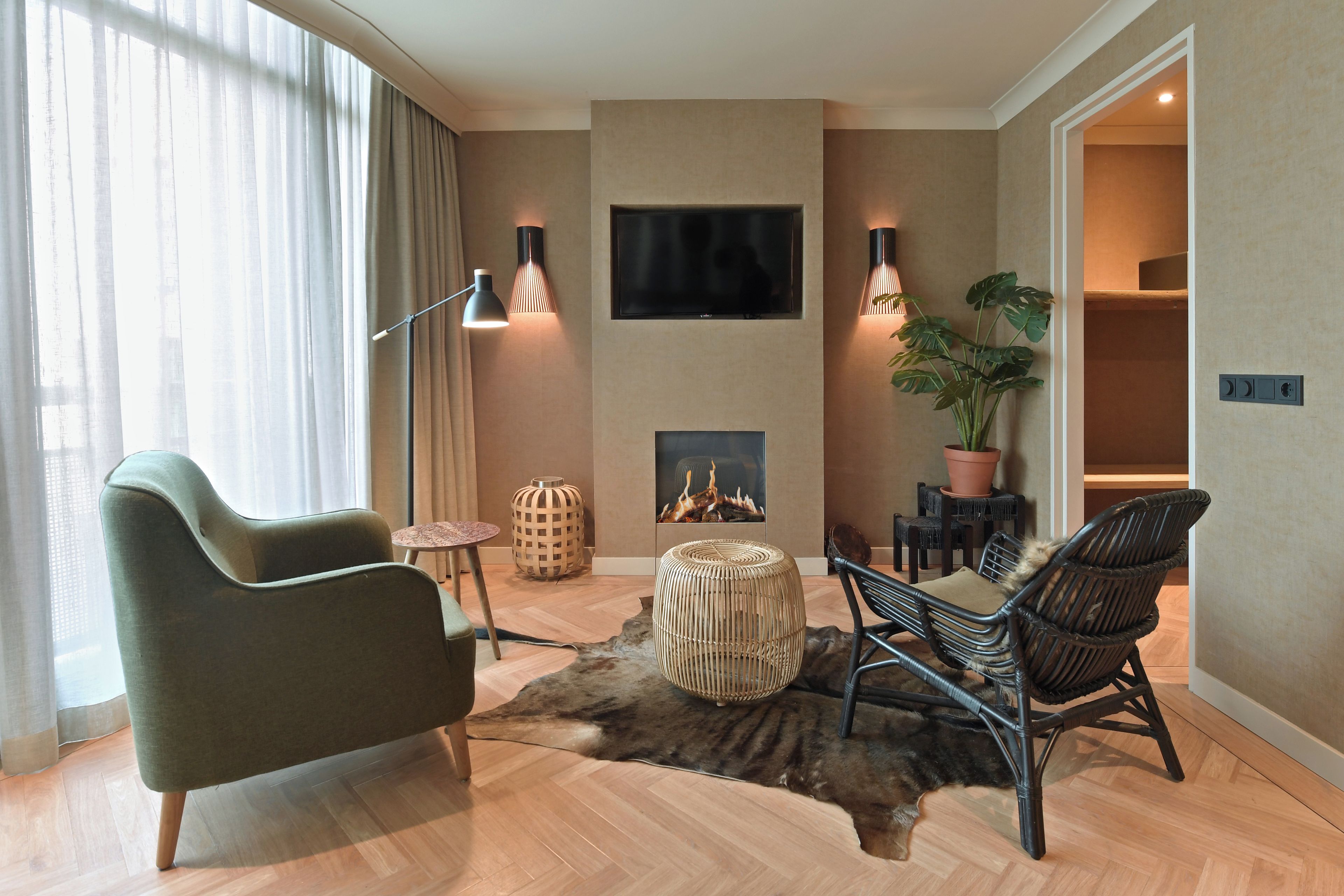 A modern living room with a sofa, chairs, a TV, and a fireplace.