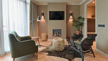 A modern living room with a sofa, chairs, a TV, and a fireplace.