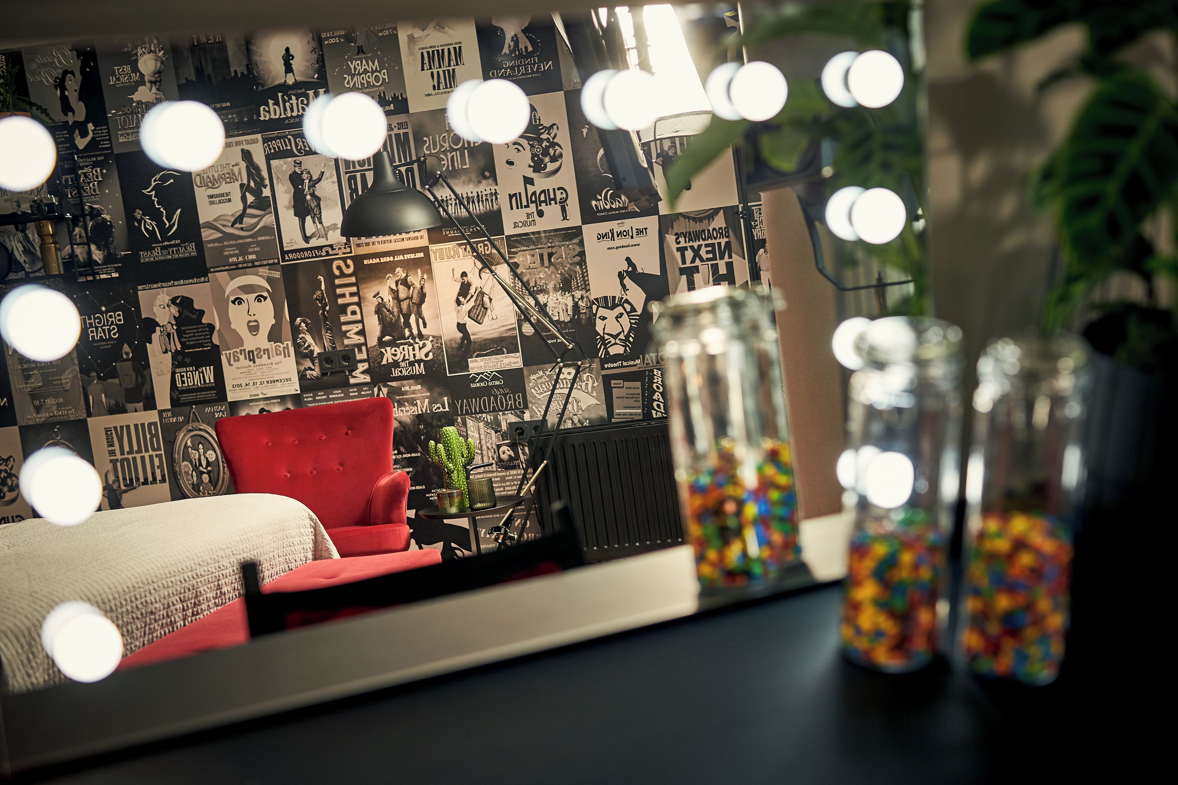 Una habitación con un sofá rojo, una lámpara negra y una pared decorada con varios carteles.