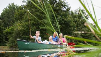 A green boat with people on it, reflecting in the water.
