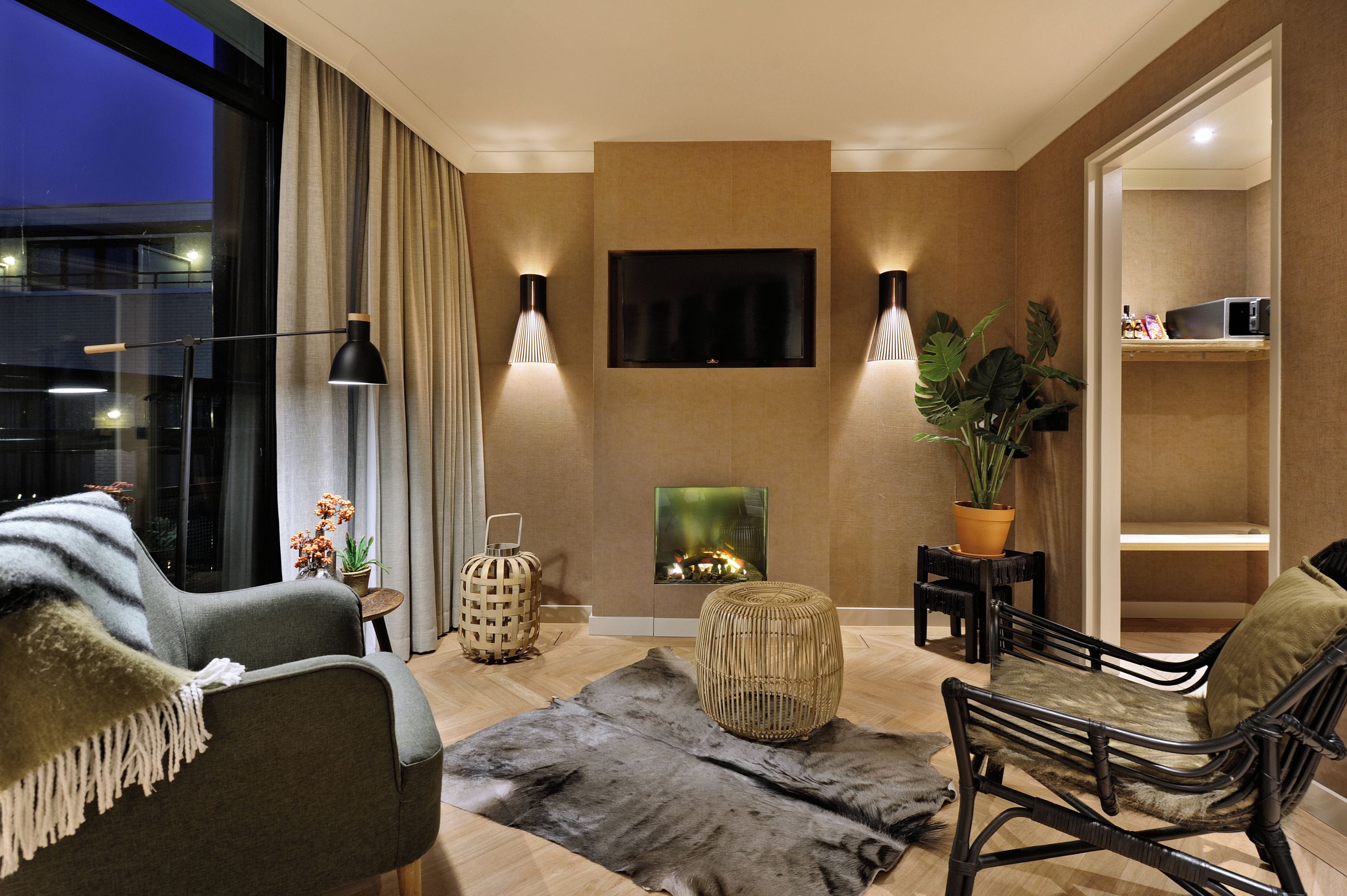 Un salon moderne doté d’une cheminée, de sièges confortables et d’un téléviseur à écran plat fixé au mur.