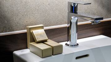 Een wastafel met een moderne kraan en een zeepdispenser.