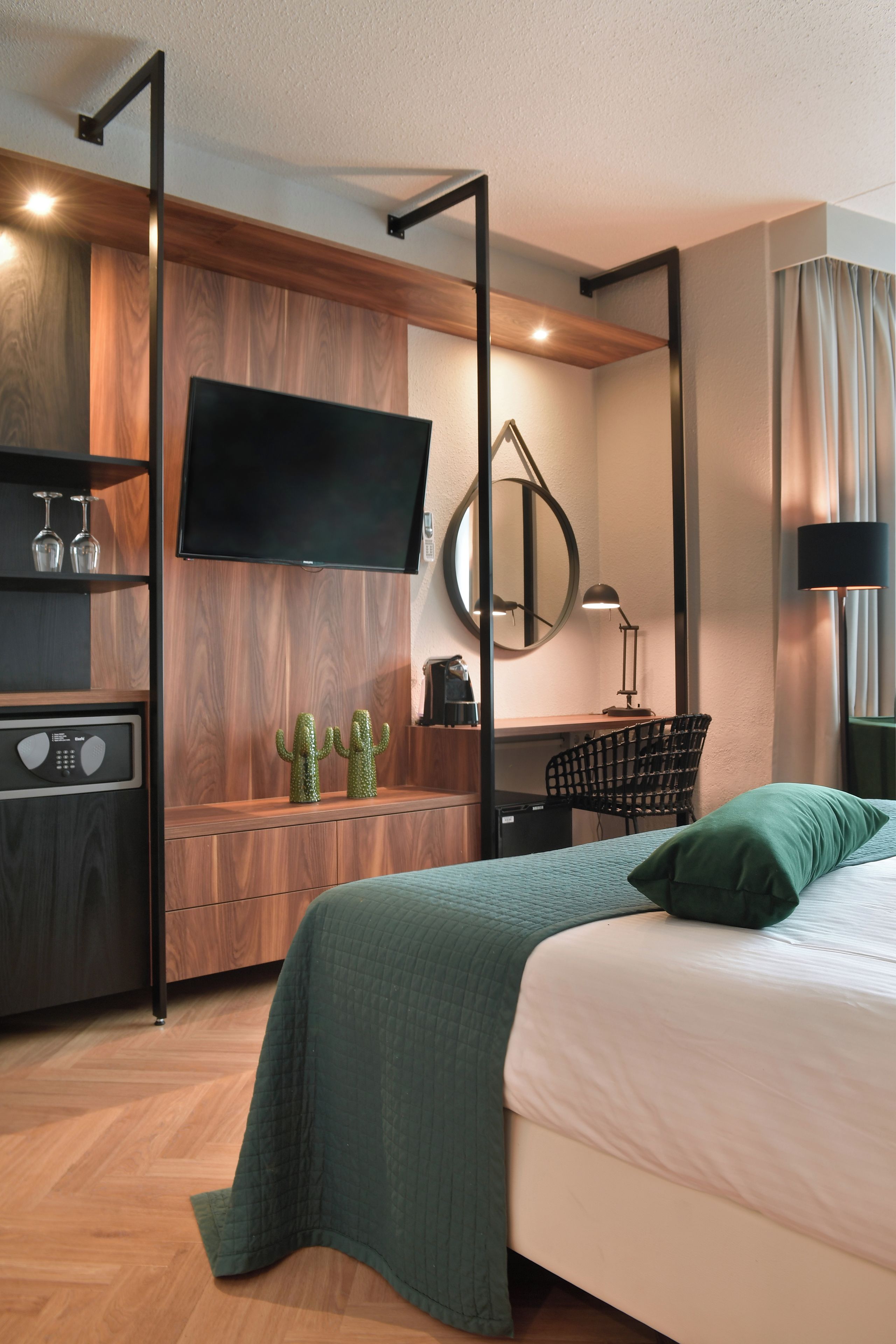 A modern hotel room with a bed, a desk, a television, a mirror, and a chair.