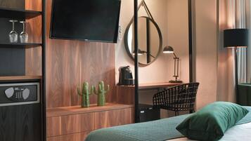 A modern hotel room with a bed, a desk, a television, a mirror, and a chair.