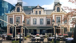 A historic building with a cafe patio featuring outdoor seating and tables.