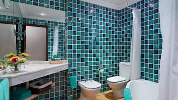 A bathroom with a tiled wall, a sink, a toilet, and a bathtub.