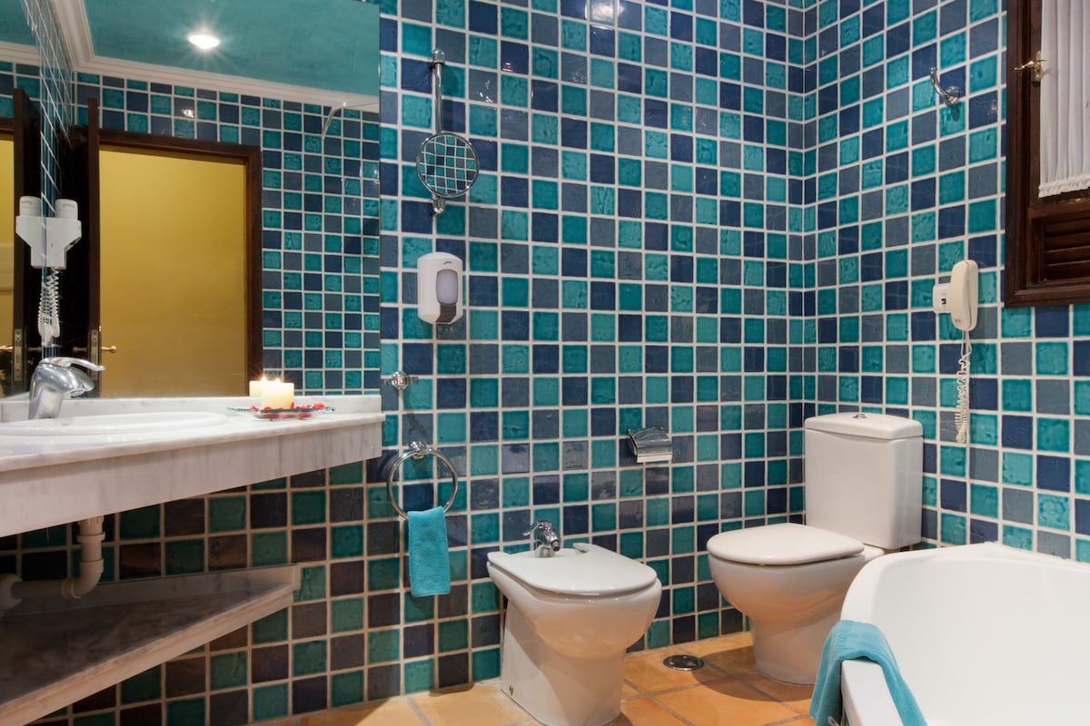 A bathroom with a tiled wall, a sink, a toilet, and a bathtub.