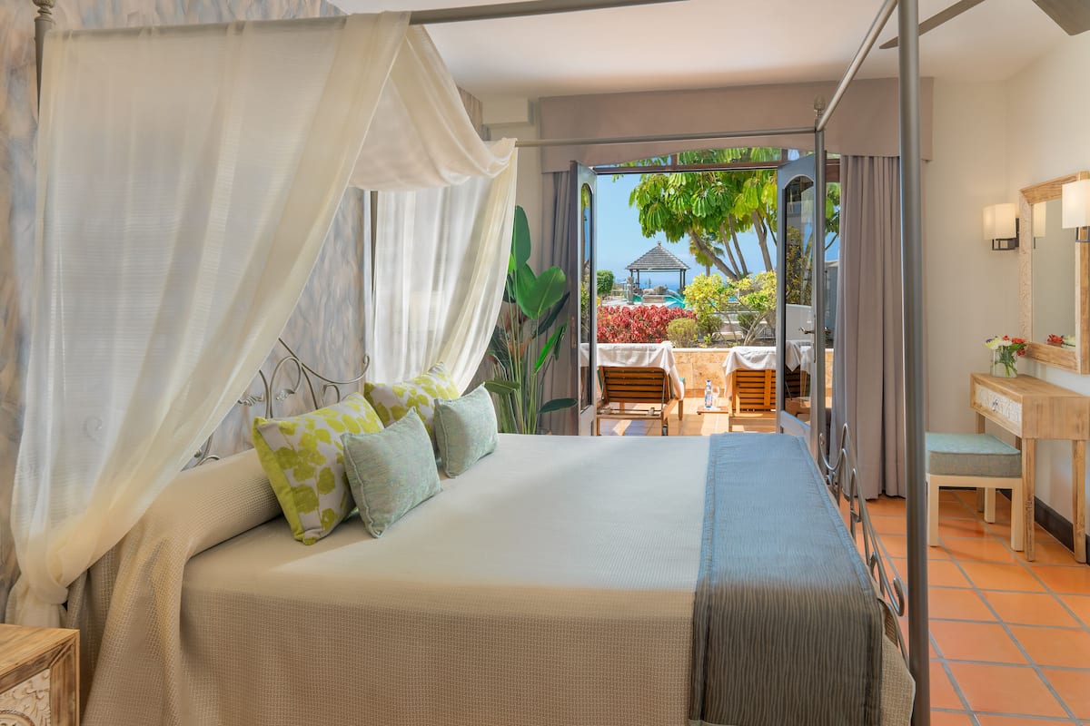A bedroom with a large bed, a desk, and a view of the outdoors.