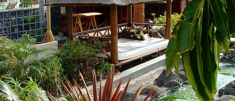 Een resort met een zwembad, palmbomen en een hut met rieten dak.