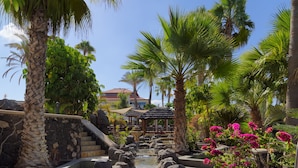 A tropical garden with a water feature, palm trees, and a gazebo. - Regency Country Club, Apartments Suites (Arona)
