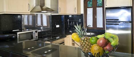 A kitchen with stainless steel appliances, wooden cabinets, and a fruit bowl on the counter.