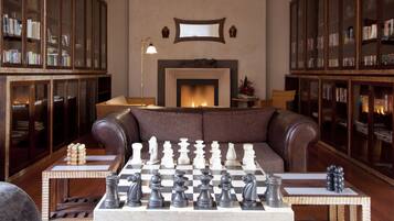 Una sala de estar acogedora con chimenea, sofá de cuero y un tablero de ajedrez.