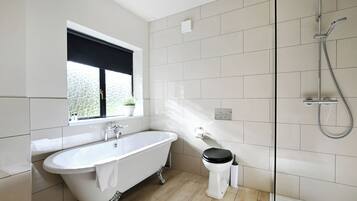 A modern bathroom with a freestanding bathtub, a toilet, and a glass-enclosed shower area.