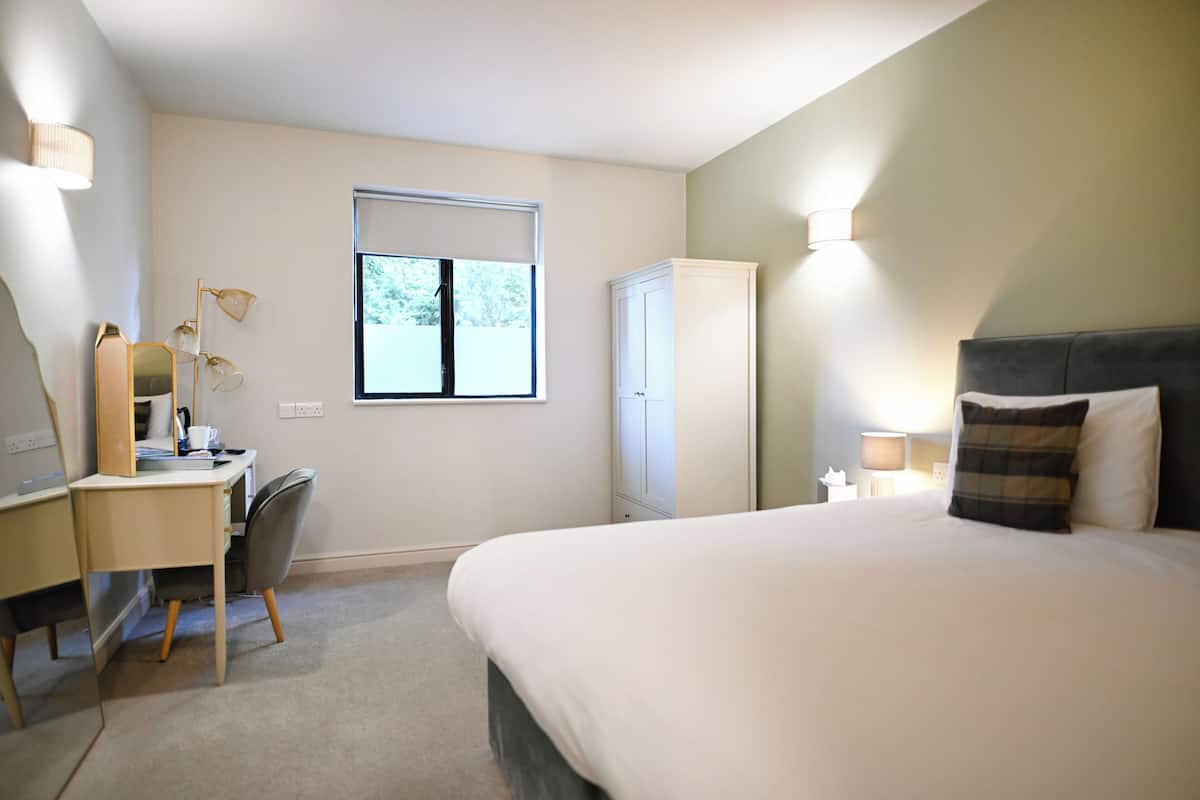 Ein Hotelzimmer mit Bett, Schreibtisch, Stuhl, Kleiderschrank und einem Fenster.