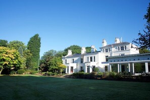A large, white, two-story building with a symmetrical facade, multiple chimneys, and a covered porch area. - Chancellors Hotel and Conference Centre (Manchester)