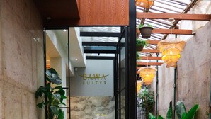 Ein moderner Hotelzugang mit Glastür, einem Schild mit der Aufschrift "Bawa Suites" und einer Reihe beleuchteter Stufen zum Eingang.