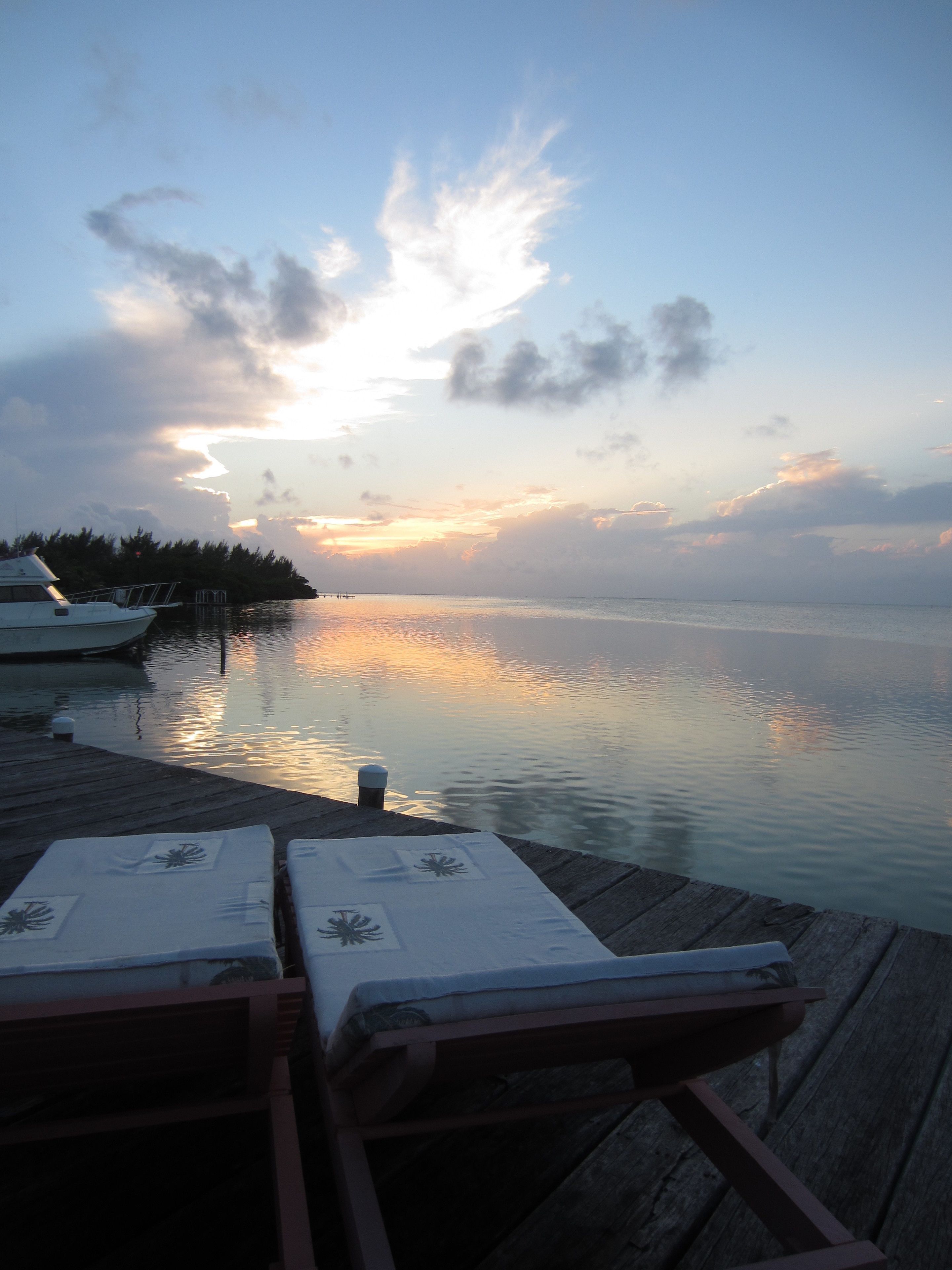 A wooden pier extending into calm waters with a sunset in the background.