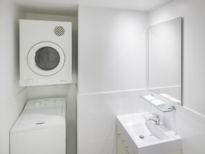 A modern bathroom with a washing machine, a glass shelf, and a sink. - Mantra Castle Hill Sydney (Castle Hill)