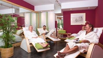 A room with reclining chairs, a large mirror, and a potted plant.