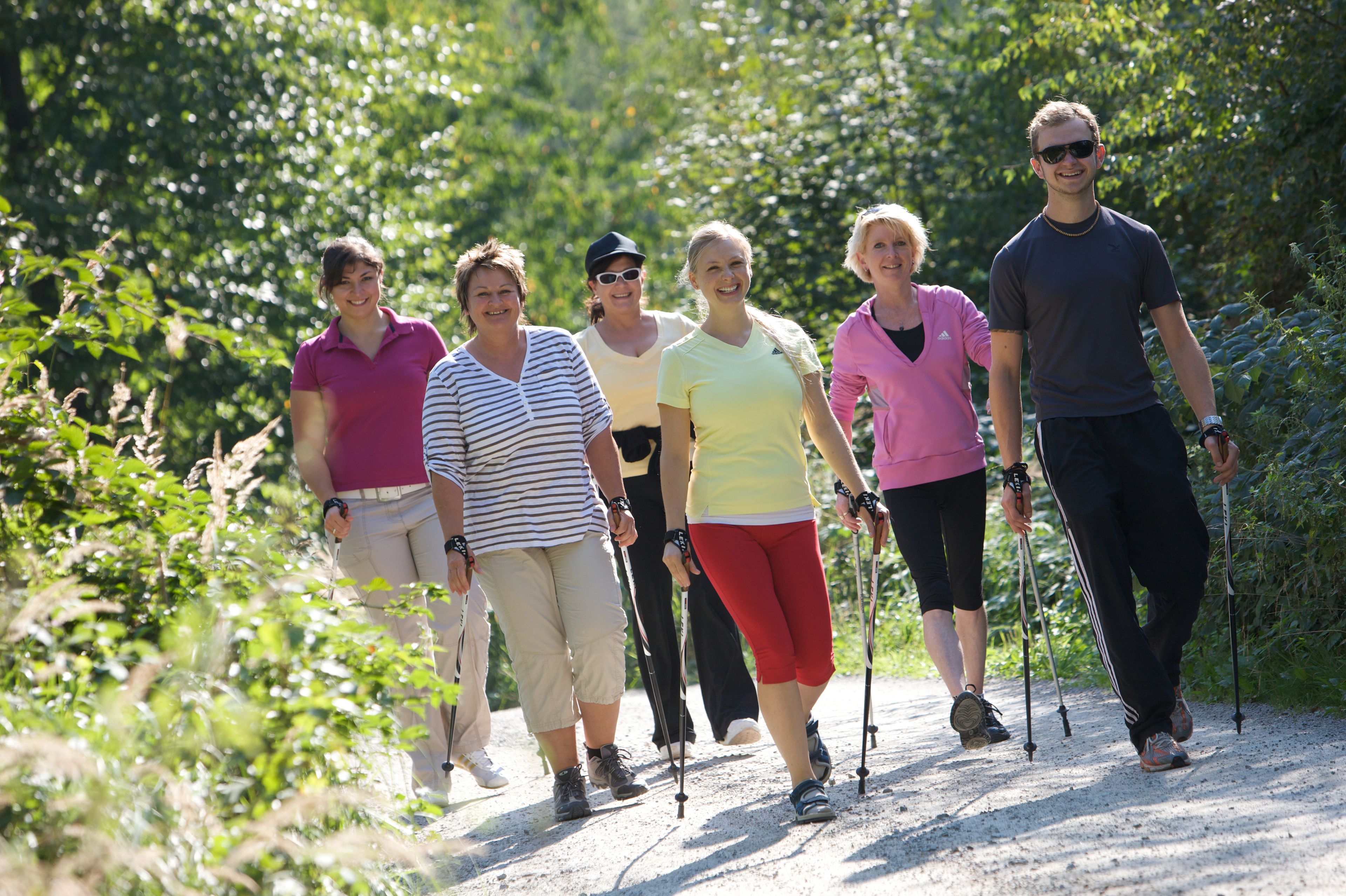 Un groupe de personnes marchant sur un sentier de terre, entouré de verdure.