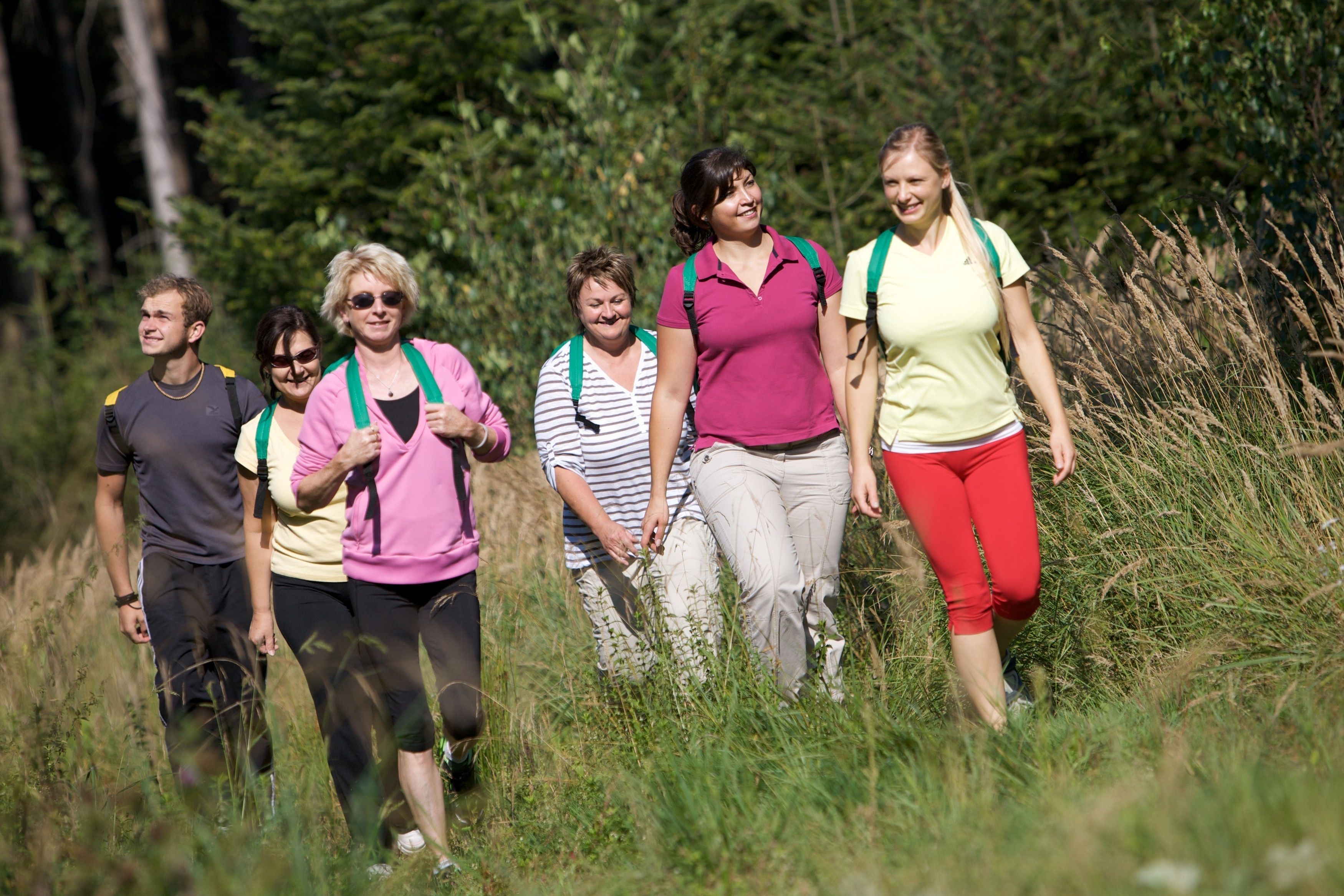 A group of people walking in a grassy outdoor area.