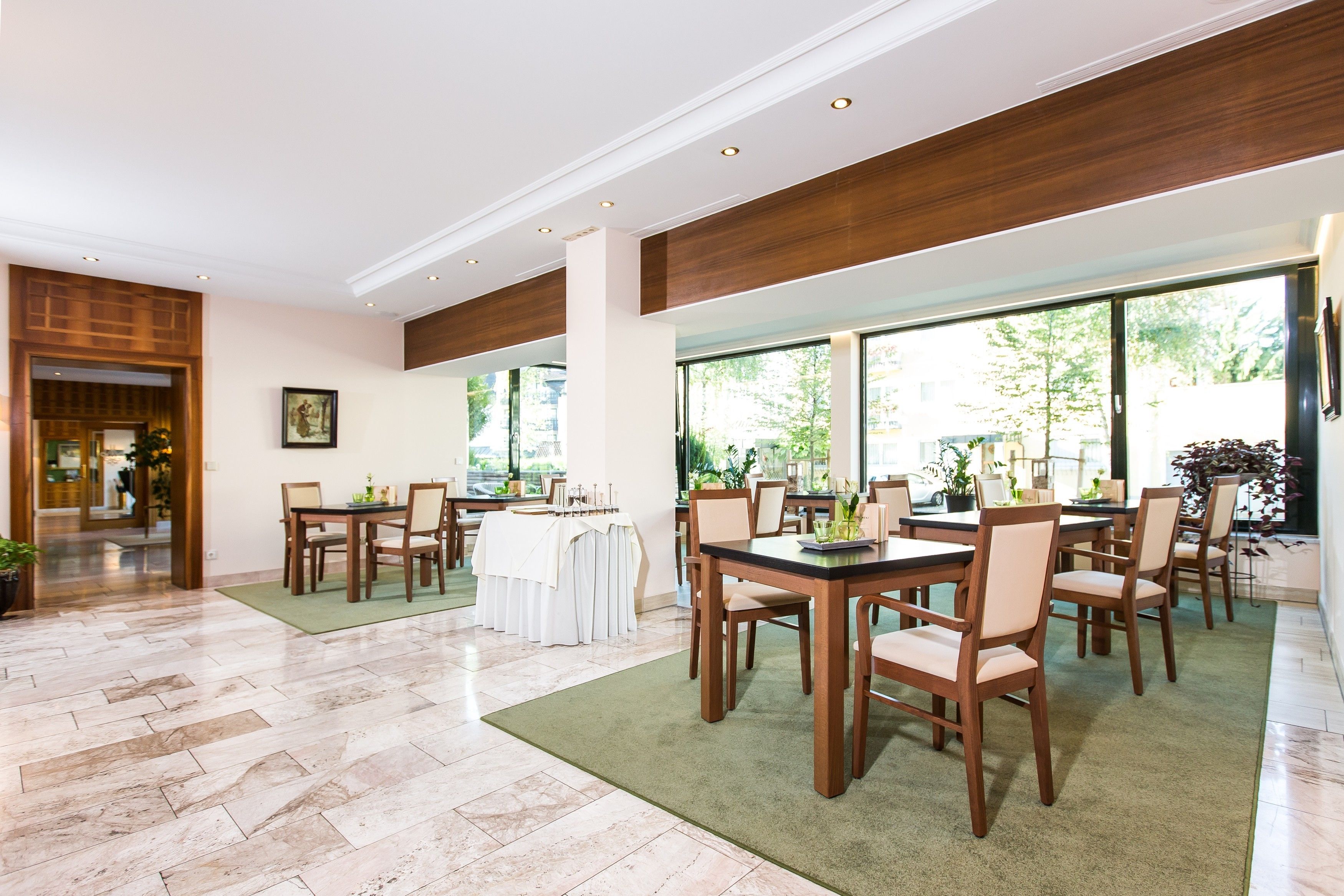 Un vaste espace dédié à la salle à manger, avec de nombreuses tables et chaises, de grandes fenêtres donnant sur l’extérieur et un plancher ciré.