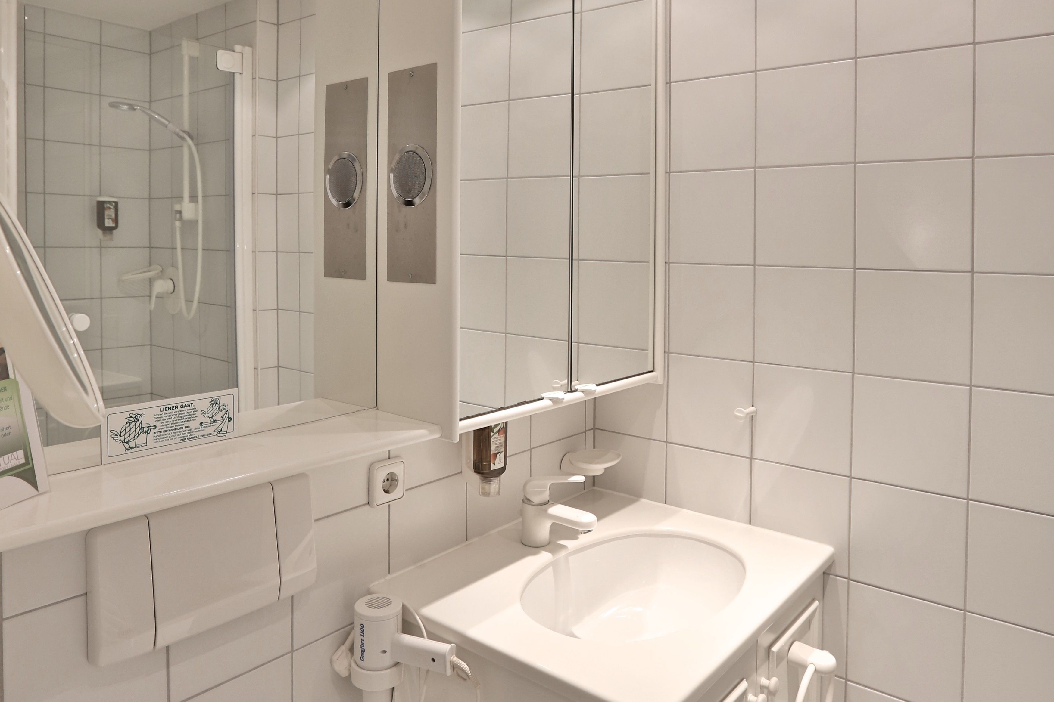 Une salle de bain moderne avec un lavabo blanc, un miroir et une douche.