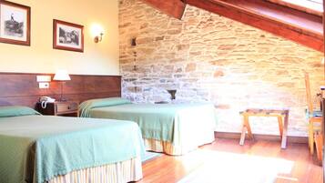 Una habitación con dos camas, pisos de madera, una pared de piedra y una viga de techo de madera.