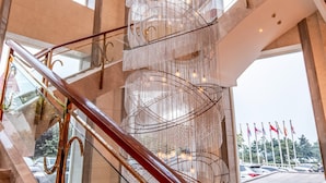 Ein modernes Interieur mit einer Wendeltreppe, Glasgeländern und einer dekorativen Metalllüster.