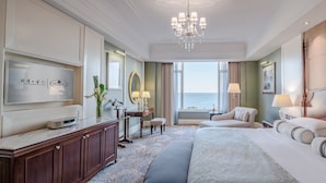 Ein Hotelzimmer mit einem großen Bett, einem Fernseher, einem Schreibtisch und Meerblick.