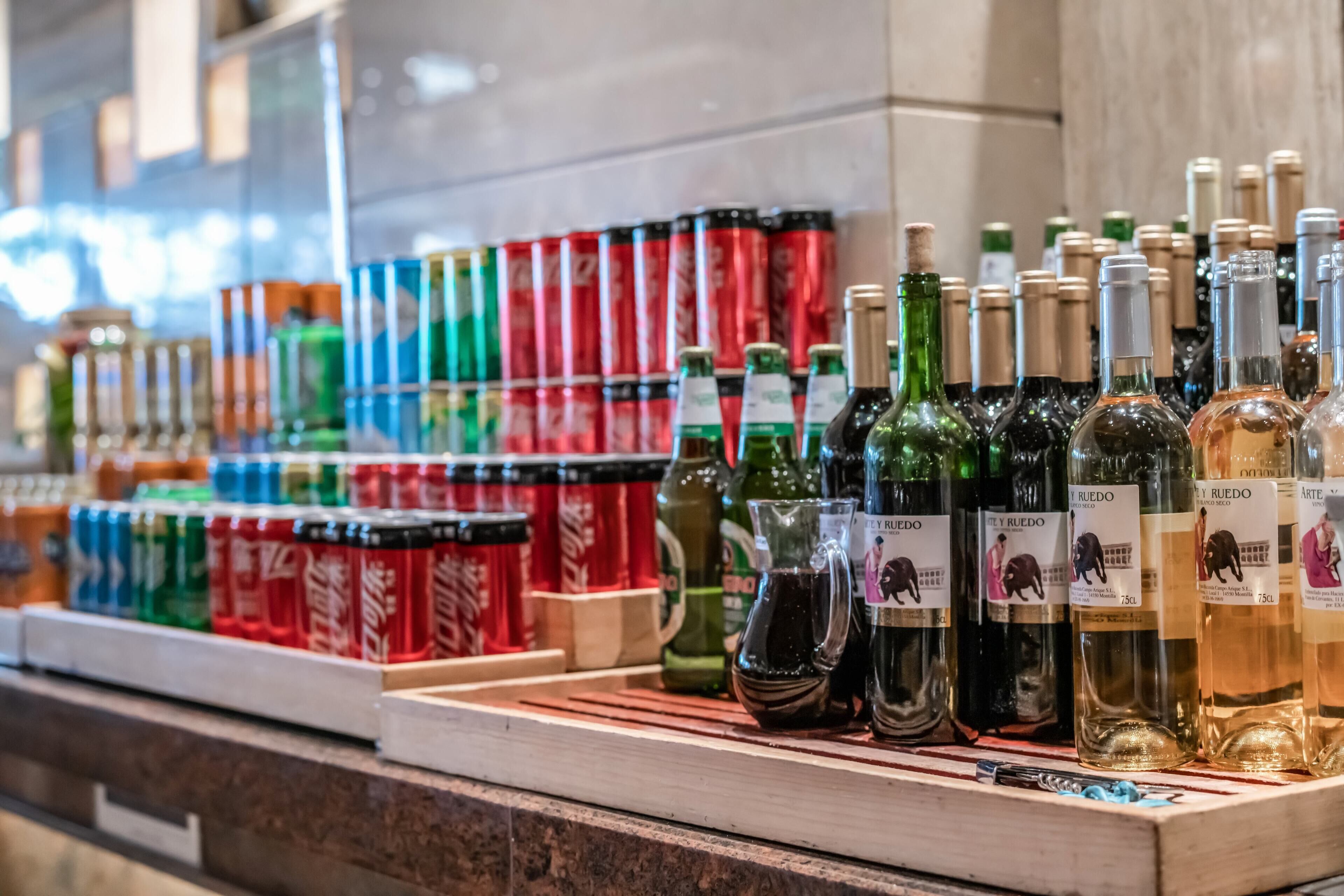 A variety of bottled beverages, including wine and soda, displayed on a counter.