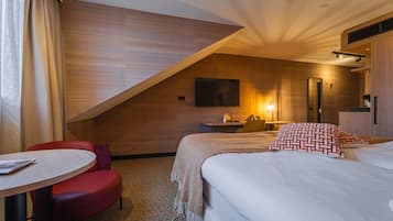 A hotel room with a bed, a desk, a chair, a television, and a mirror.