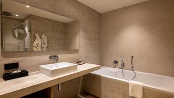 Un baño moderno con un espejo grande, dos lavamanos, una bañera y toallas.