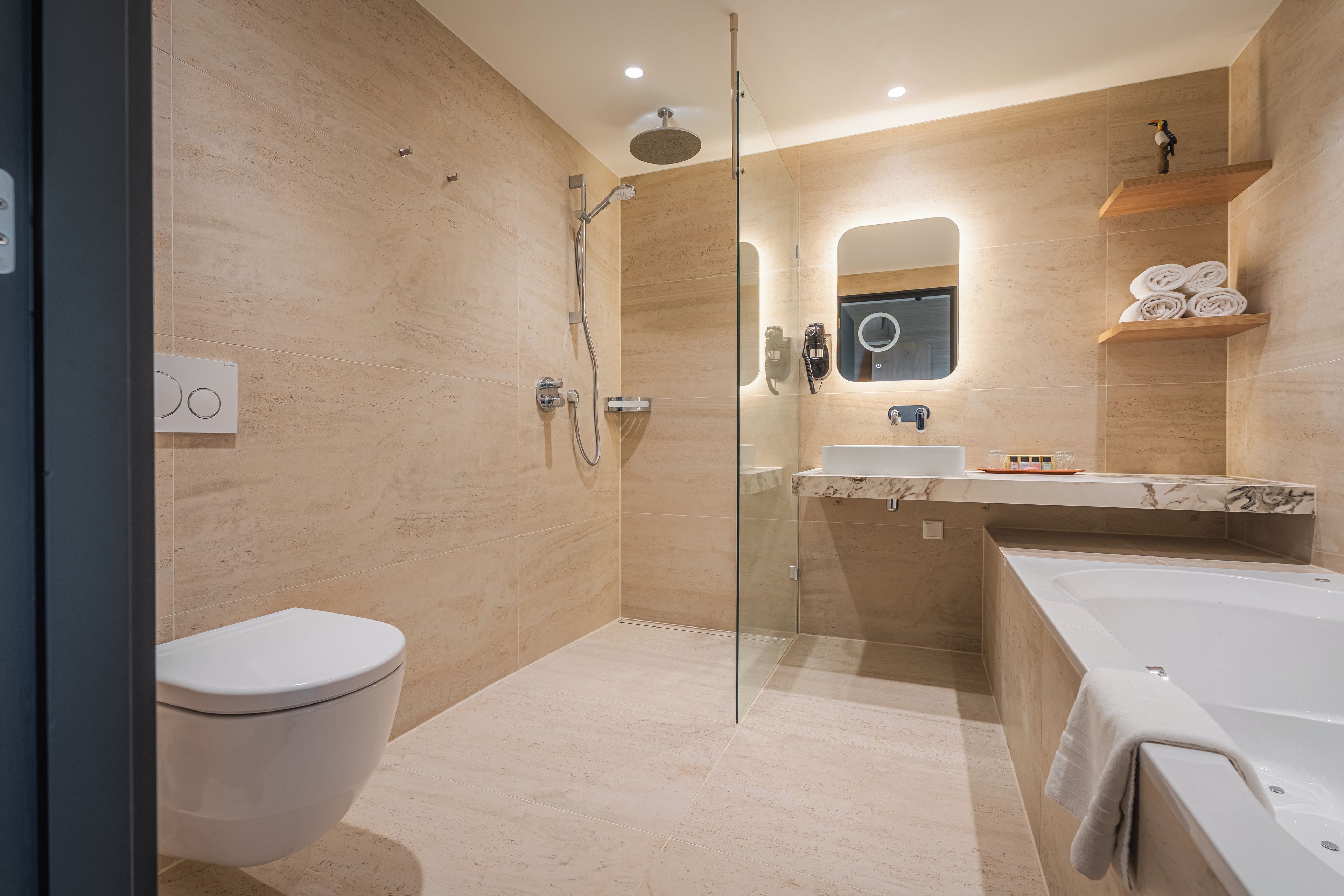 A modern bathroom with a glass-enclosed shower, a toilet, a sink with a marble countertop, and a bathtub.