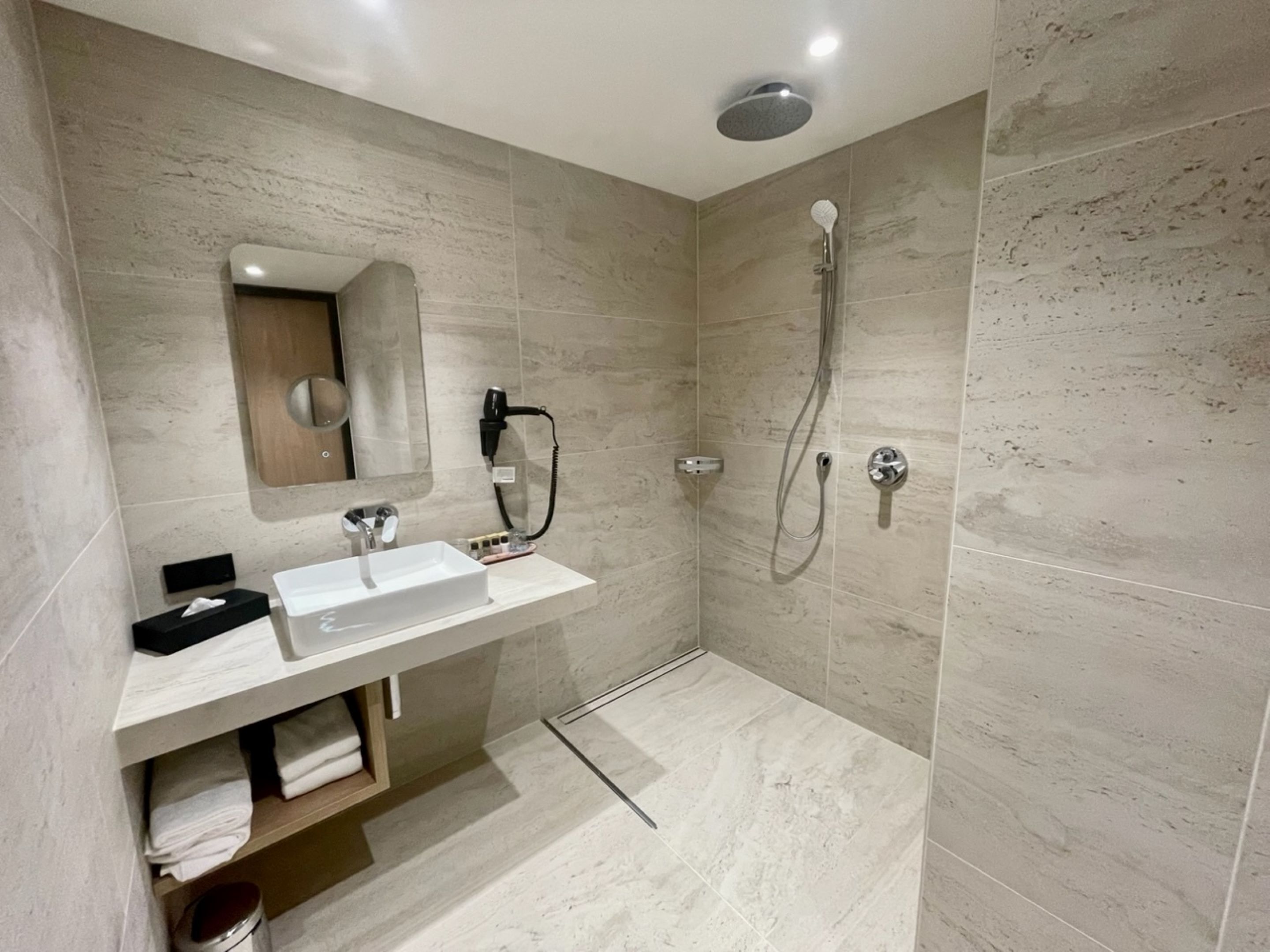 Ein modernes Badezimmer mit Waschbecken, Spiegel und Dusche in Weiß.