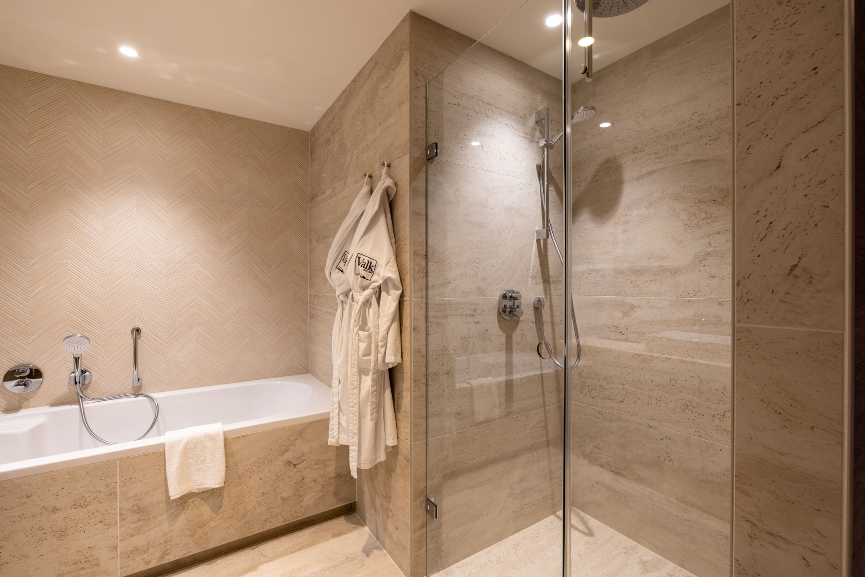 Une salle de bain moderne dotée d’une douche à parois de verre, d’une baignoire sur pieds et d’un porte-serviettes avec plusieurs serviettes.