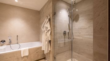 Ein modernes Badezimmer mit einer Glaskabinentrennwand, einer freistehenden Badewanne und einem Handtuchhalter mit mehreren Handtüchern.