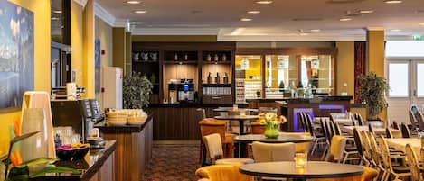 Vestíbulo de hotel con área de bar, asientos y mostrador de recepción.