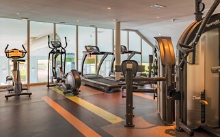 Gimnasio con cintas de correr, elípticas y equipo de pesas.