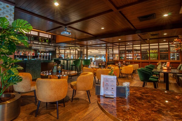 A restaurant with wooden ceiling, bar area, seating with green and yellow chairs, and a menu stand. - Van Der Valk Hotel Hengelo (Hengelo)