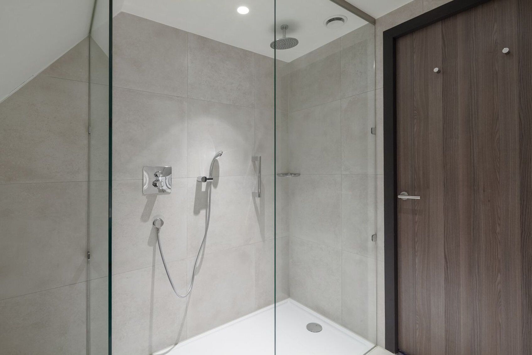 Un espace douche moderne avec une paroi en verre, une porte en bois et une baignoire blanche.