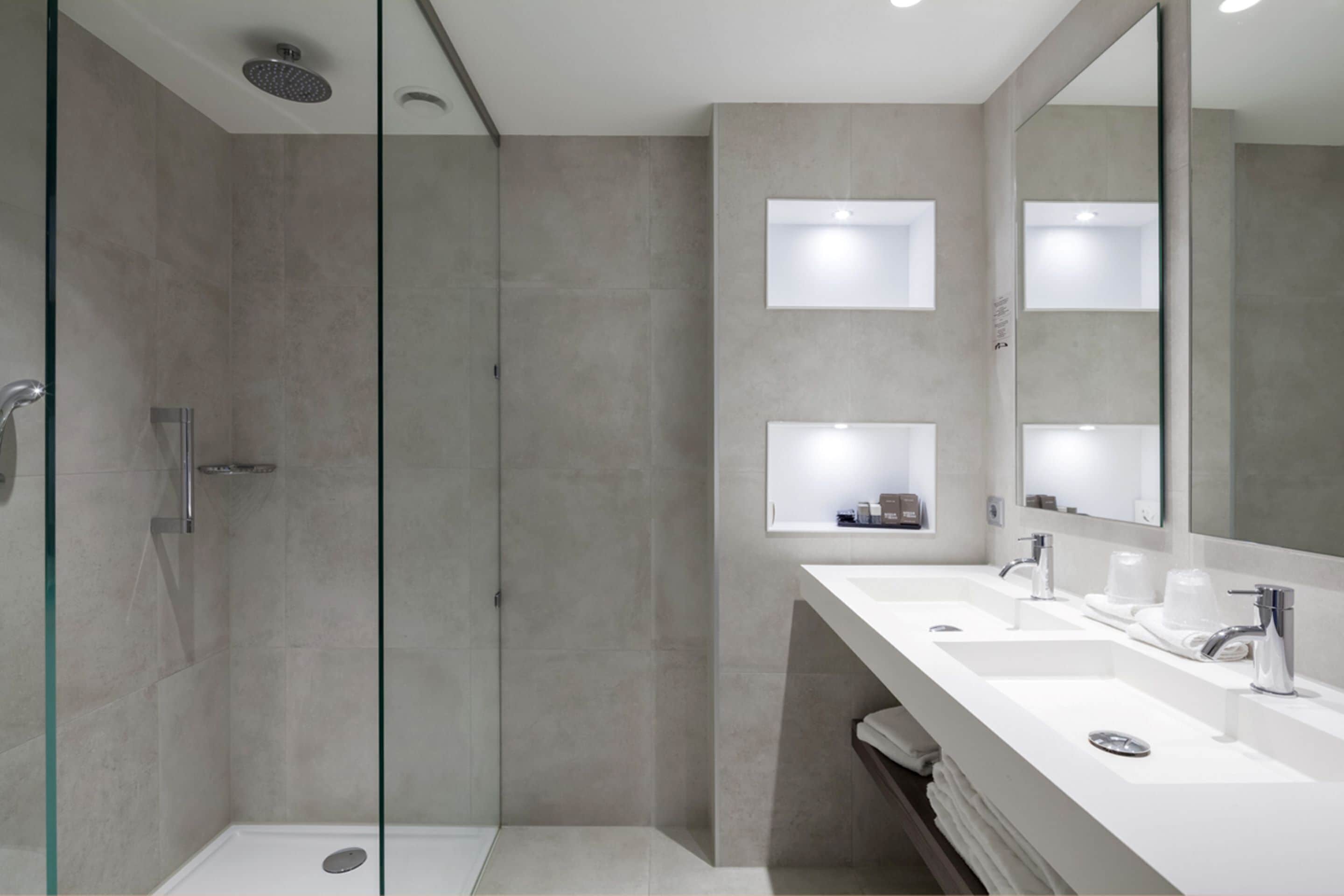 A modern bathroom with a glass-enclosed shower, two sinks, and a large mirror.