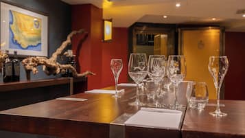 A bar area with multiple wine glasses and bottles, a framed map on the wall, and a wooden counter.
