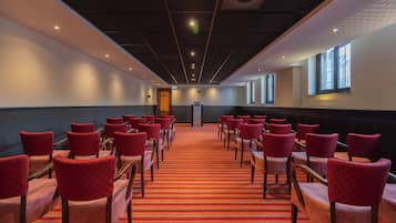 A conference room with rows of red chairs and a red carpet.
