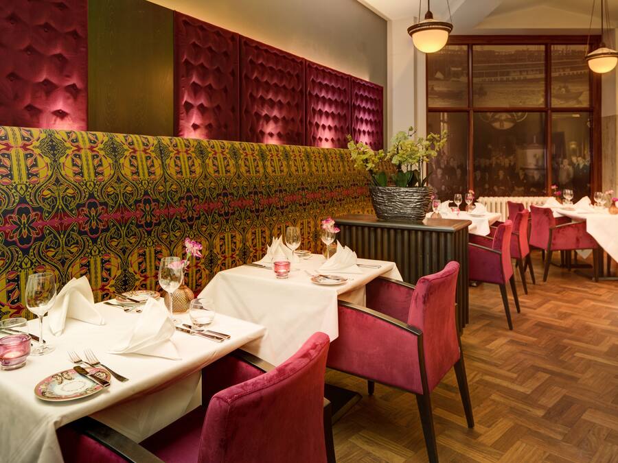 Interior de restaurante con mesas dispuestas para comer, un muro con diseño y un amplio ventanal con vistas.