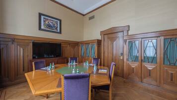 A conference room with a large wooden table, chairs, a television, and a framed picture on the wall.