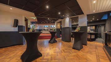 A modern interior with black tables and a wooden herringbone floor.