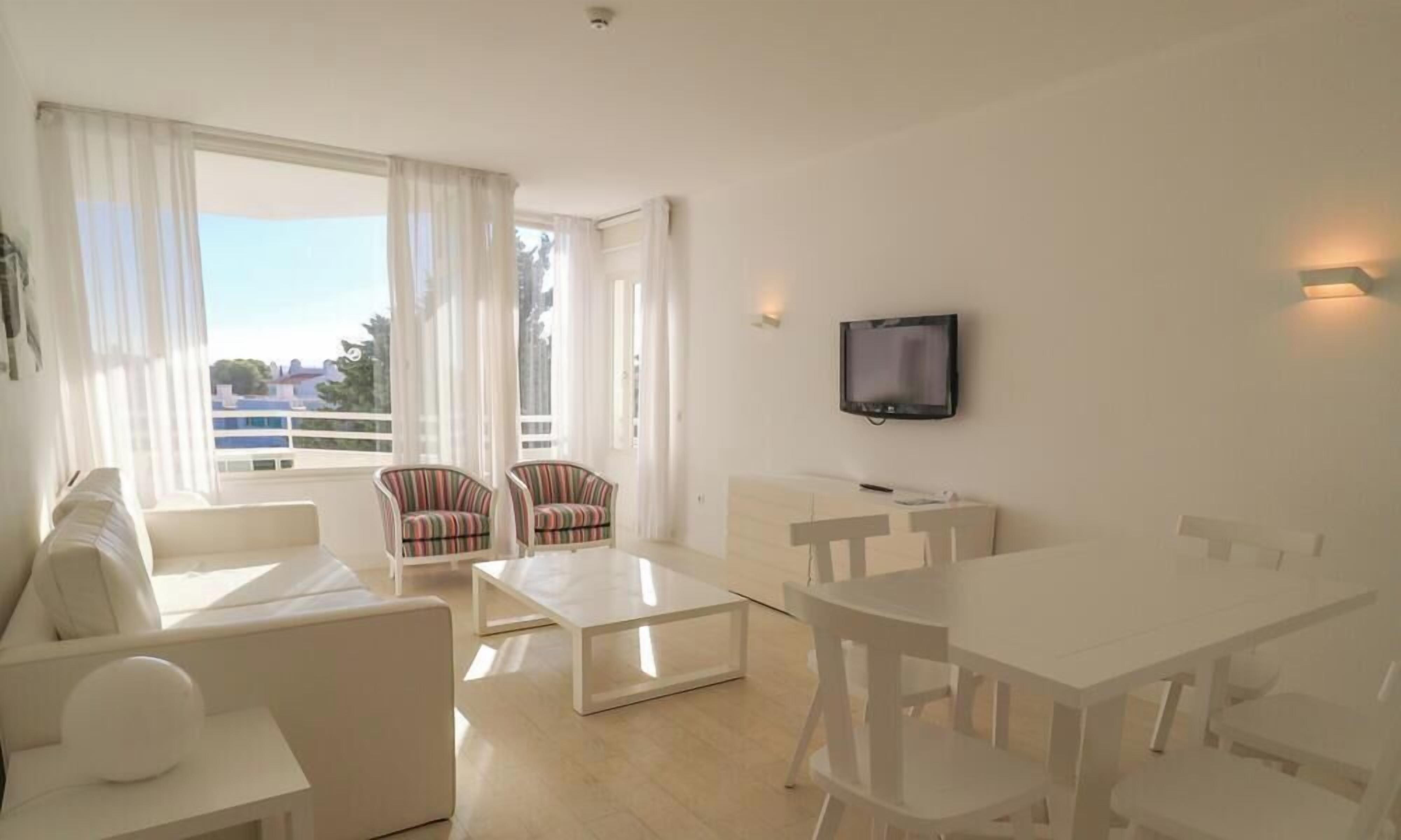 A modern living room with a sofa, armchair, coffee table, dining table, and TV.