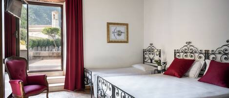 A room with a bed, a chair, and a window with curtains.