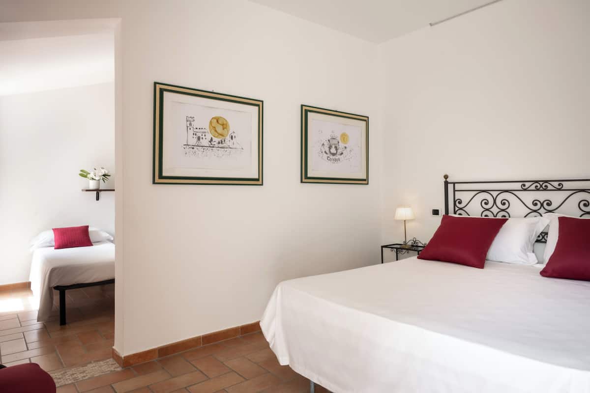A bedroom with a large bed, a smaller bed, and two framed pictures on the wall.